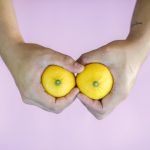 Two hands holding lemons that seem to look like a pair of breasts.