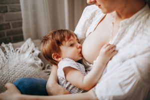 woman in white tank top carrying baby in black and white stripe onesie